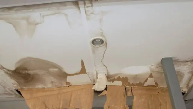 Water-damaged ceiling with a cut-out section and stained drywall